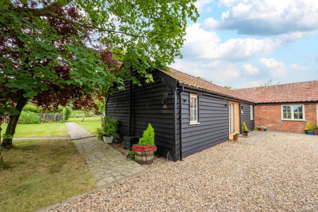 a black house with a garden in front of it at Sundial Lodge in Wilby