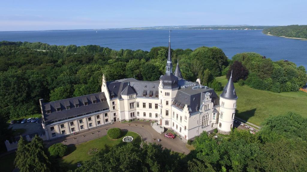 eine Luftansicht eines Schlosses auf einem Hügel neben dem Wasser in der Unterkunft Schlosshotel Ralswiek in Ralswiek