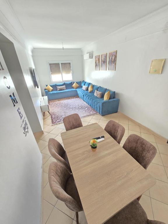 a living room with a table and a blue couch at AGADIR apparemment du LUX in Agadir