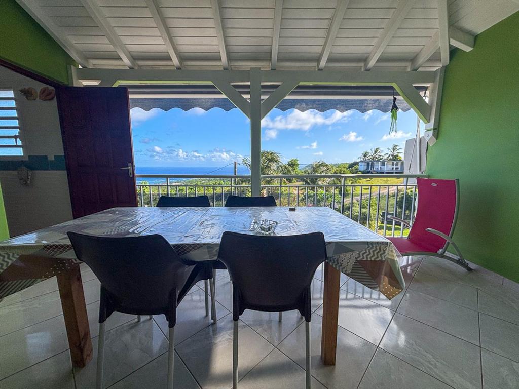 a dining room table with chairs and a view of the ocean at Gîte Soleil Canne in Capesterre-de-Marie-Galante