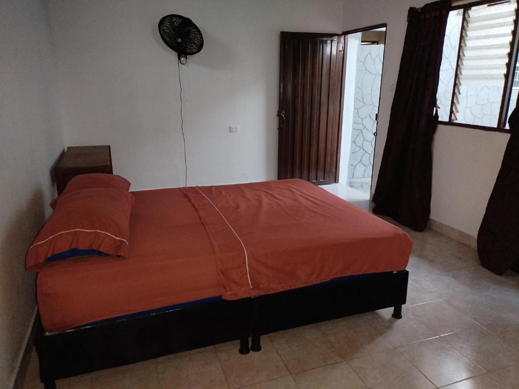 a bedroom with a bed with an orange comforter at Casa Zona Rosa in La Dorada