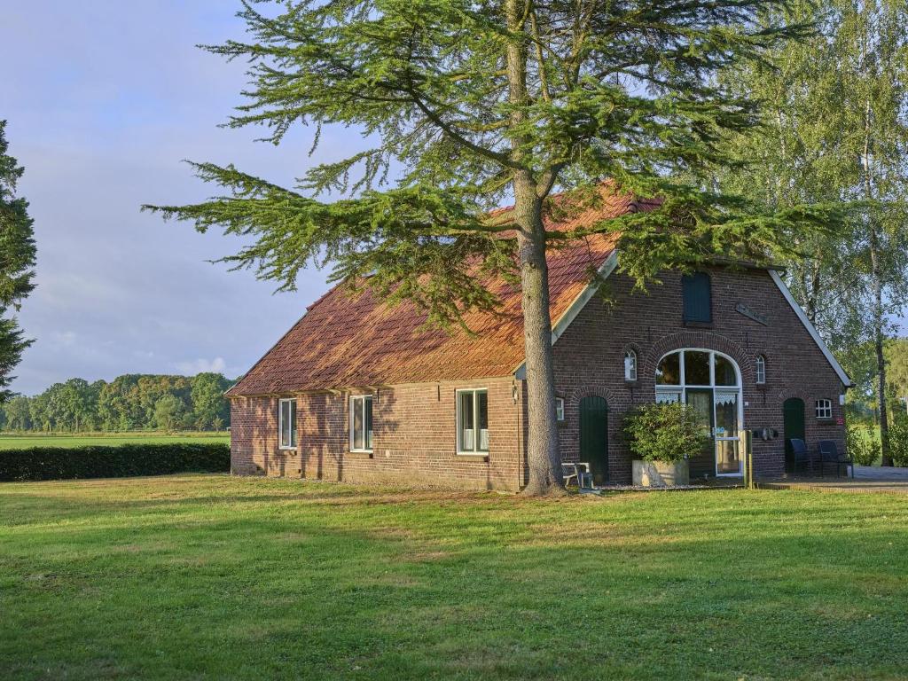 an old brick house with a tree in a field at Erve Koeleman in Neede