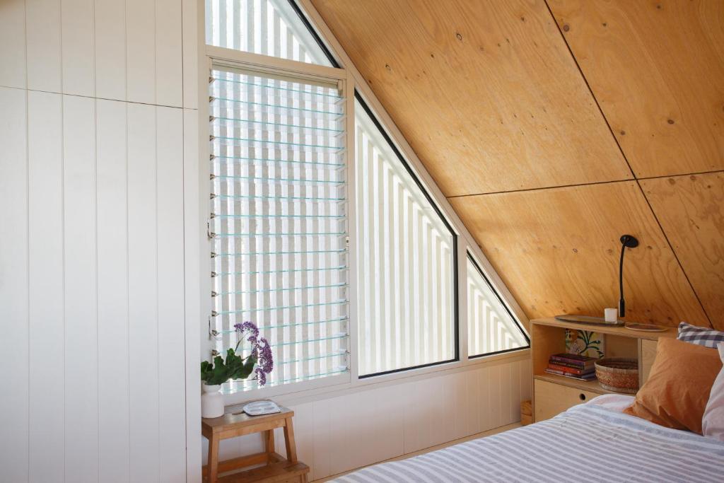 Un dormitorio con dos grandes ventanales y una cama. en The Hillside Project, en Frankston South
