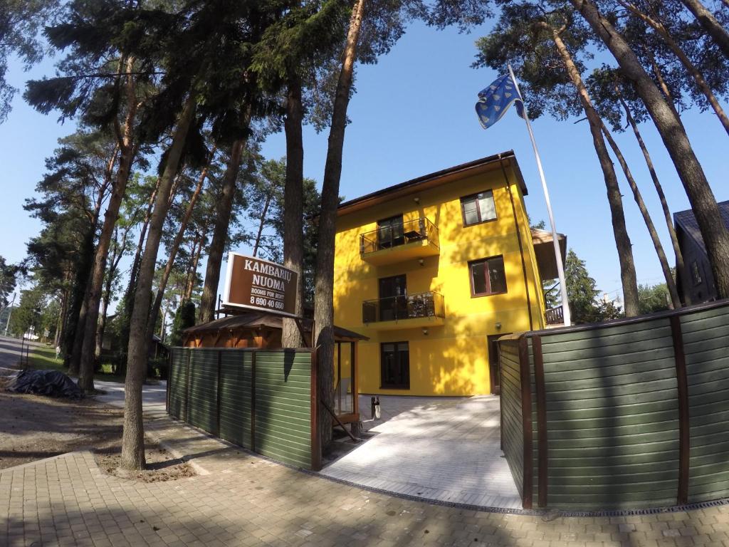 un edificio giallo con recinzione e alberi di Kambarių nuoma Kačerginės kurorte a Kačerginė