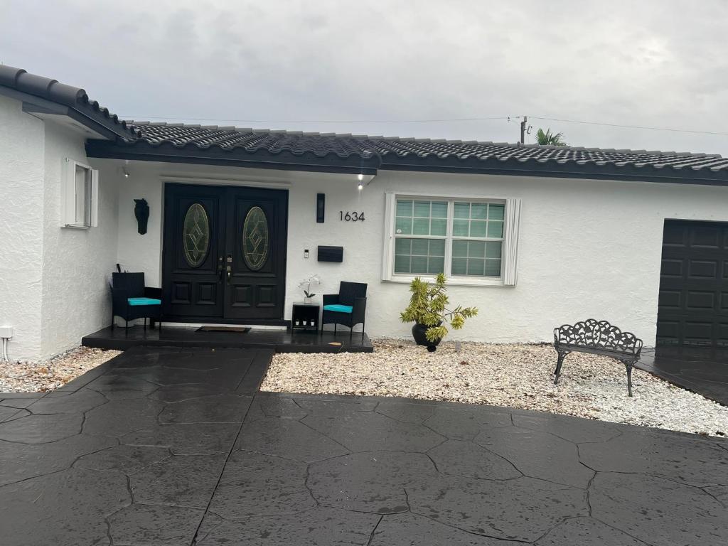 a white house with a black door and a bench at Room in Miami