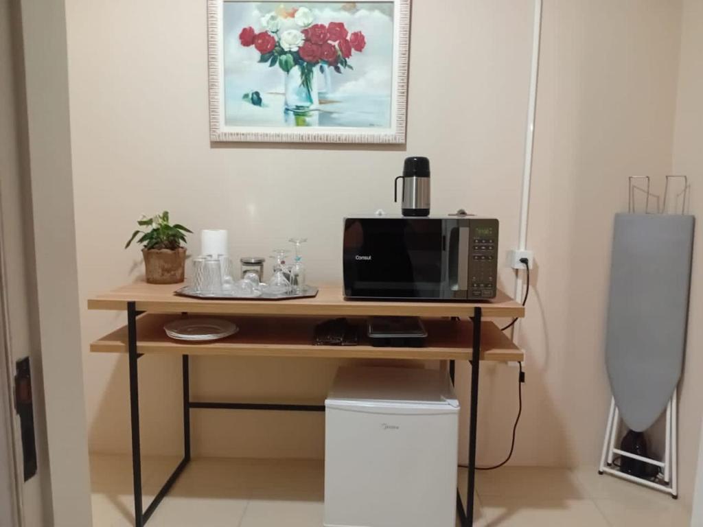 a desk with a microwave and a computer on it at Quarto Privativo ao lado do Aeroporto in Sao Jose do Rio Preto