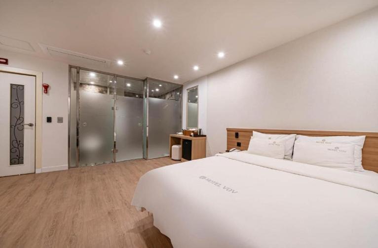 a bedroom with a large white bed and sliding glass doors at Vov Hotel in Busan