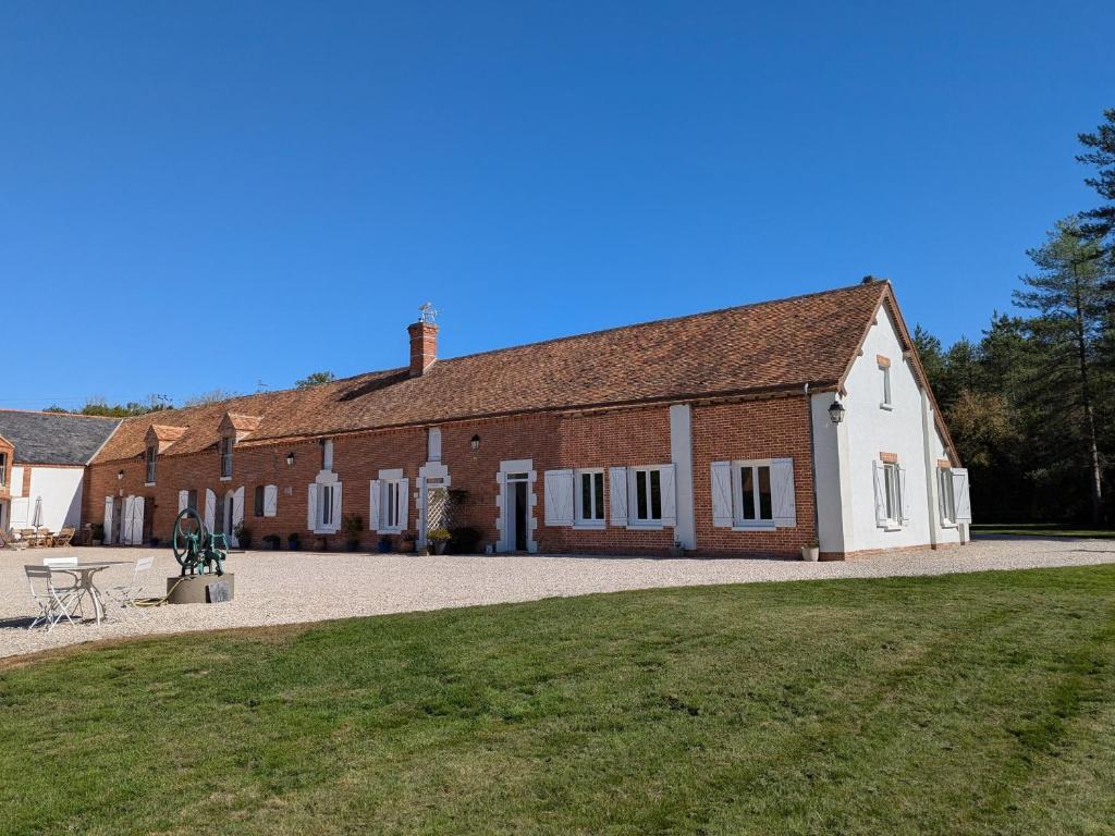 ein großes Backsteingebäude mit einem Tisch davor in der Unterkunft Gîte en Sologne au calme avec étang, proche d'Orléans et châteaux, idéal randonnées et pêche - FR-1-590-242 in Vannes-sur-Cosson