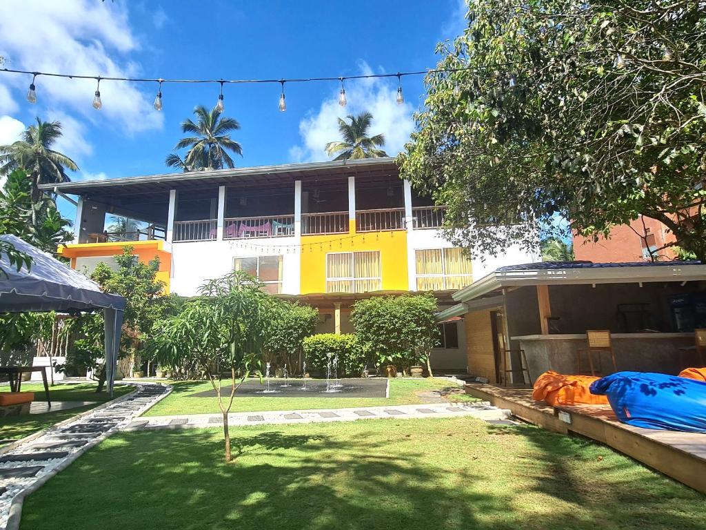 a yellow and white building with a green yard at Hotel Good Life Unawatuna in Unawatuna