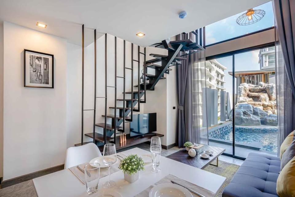 a living room with a spiral staircase and a table and chairs at Utopia Lofts by Sabai Sands in Nai Harn Beach