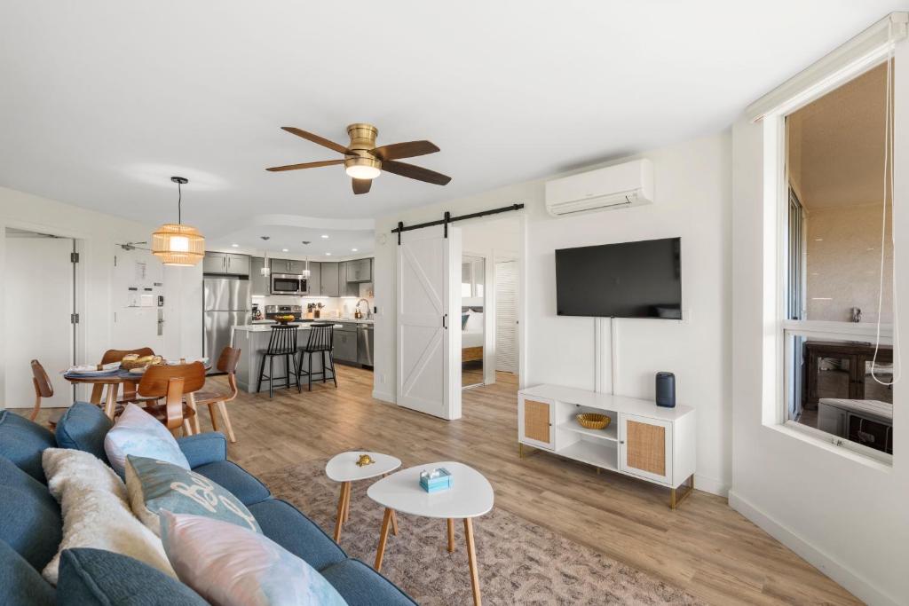 a living room with a blue couch and a tv at Elegant Maui Banyan, Pool, Hot Tub, Across Kamaole II Beach Park in Wailea