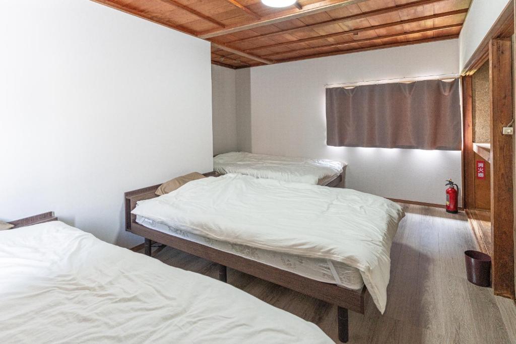 Habitación con 2 camas individuales y sábanas blancas. en ALLEY HOUSE-nachikatsuura, en Nachikatsuura