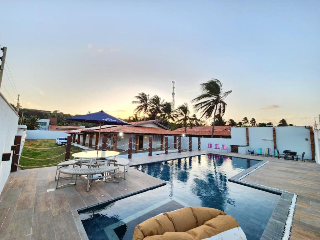 une piscine avec une table et des chaises à côté d'un bâtiment dans l'établissement Casa Maré Panaquatira, à São José de Ribamar