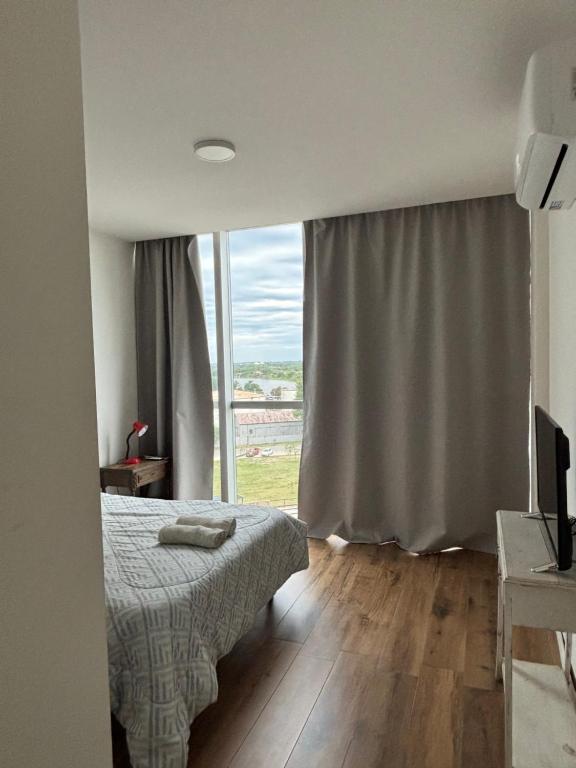 a bedroom with a bed and a large window at Depto en Garden Puerto Santa Fe in Santa Fe