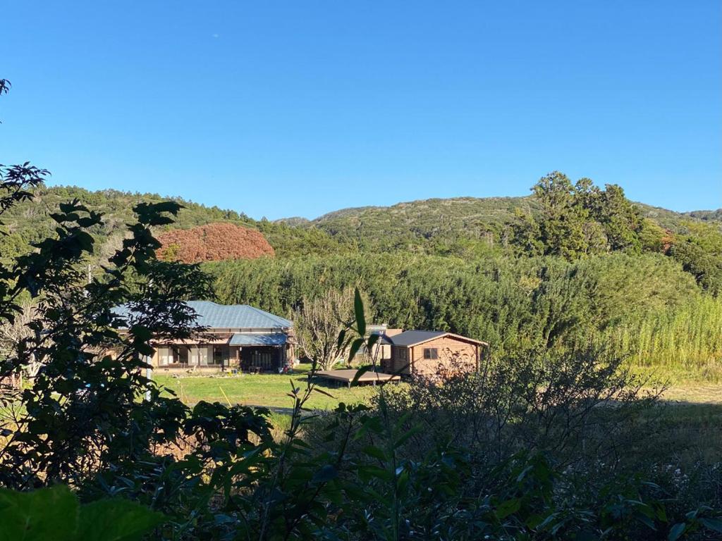 uma casa num campo com montanhas ao fundo em SUNAORetreat奥白浜 em Minamiboso