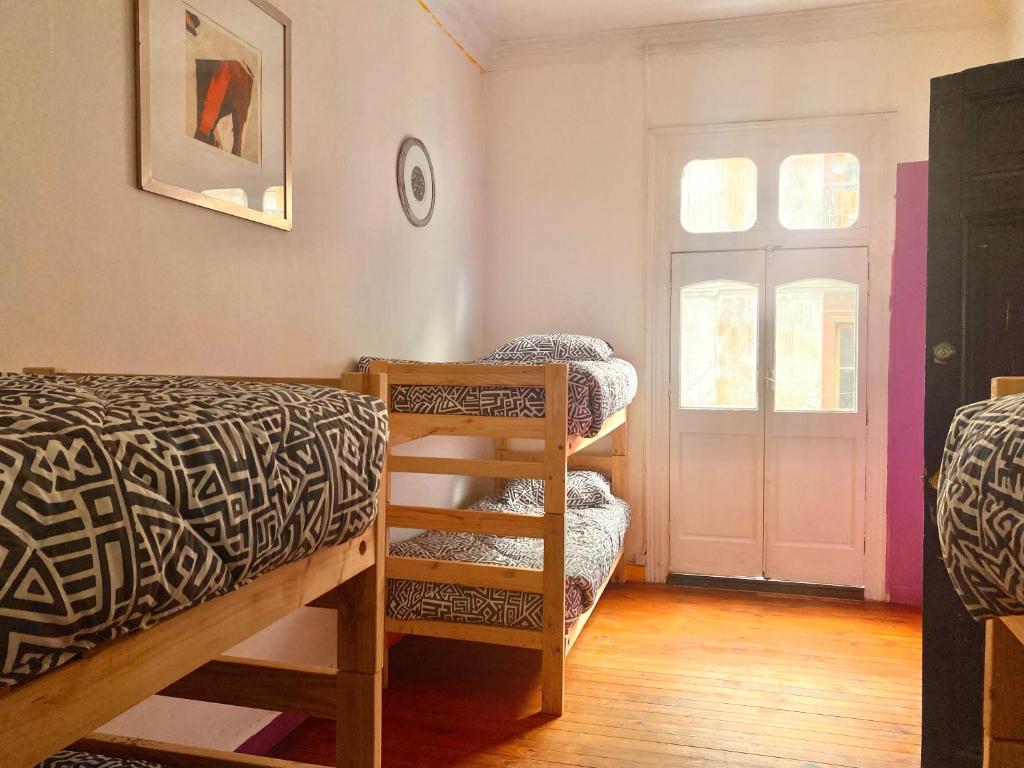 a room with three bunk beds and a door at La Mancha Art Hostel in Valparaíso
