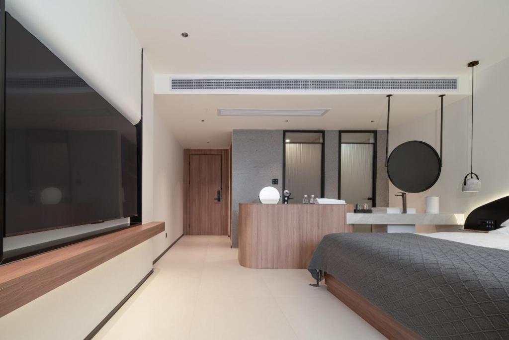 een slaapkamer met een grote televisie en een badkamer bij Karst Scenic Hotel in Gaotian