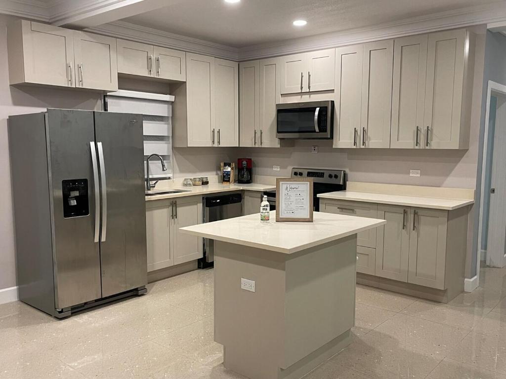 a kitchen with white cabinets and a stainless steel refrigerator at Dream Diamond in Saint Annʼs Bay