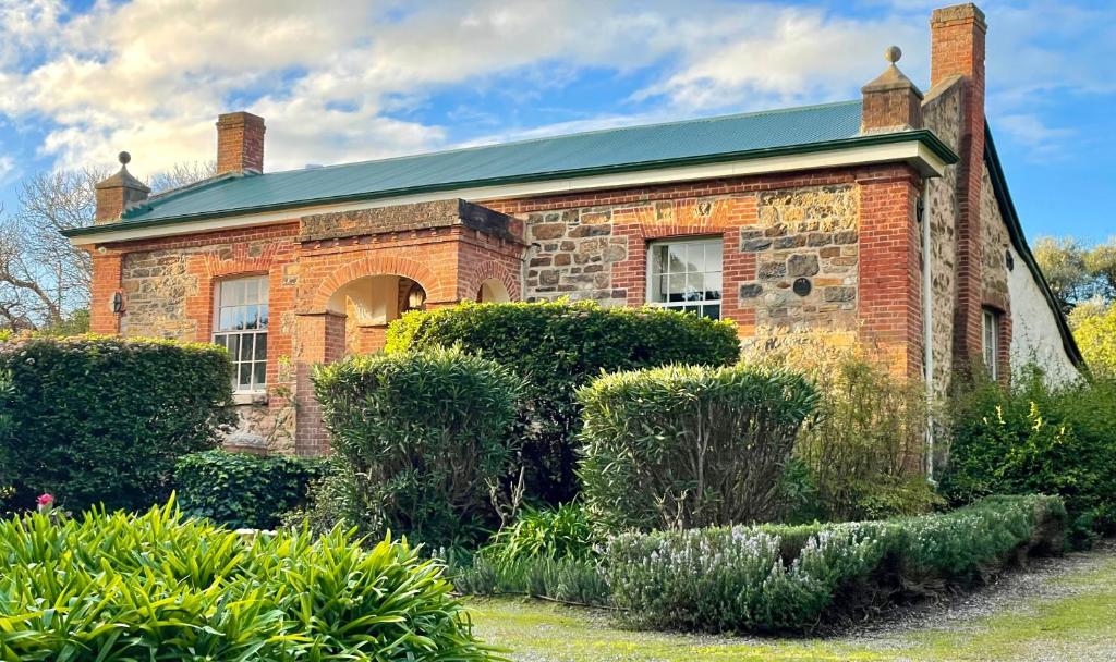 a brick house with bushes in front of it at The Olives Heritage House in Yankalilla