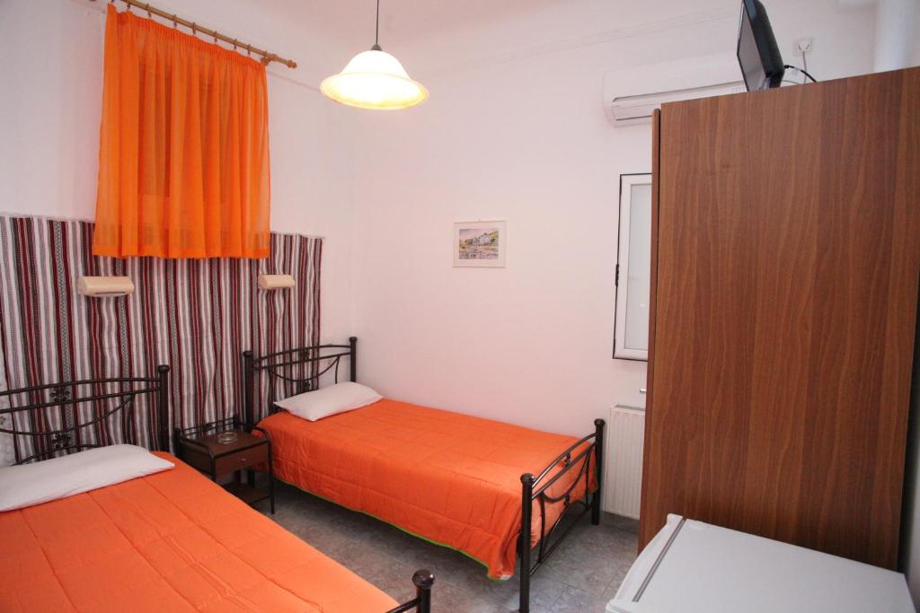 Habitación con 2 camas y cortina de color naranja en Afroditi, en Ermoupoli