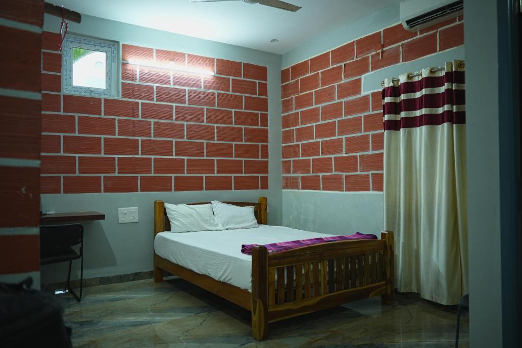 a bed in a room with a brick wall at The Hills Studio Appartment in Tiruvannāmalai