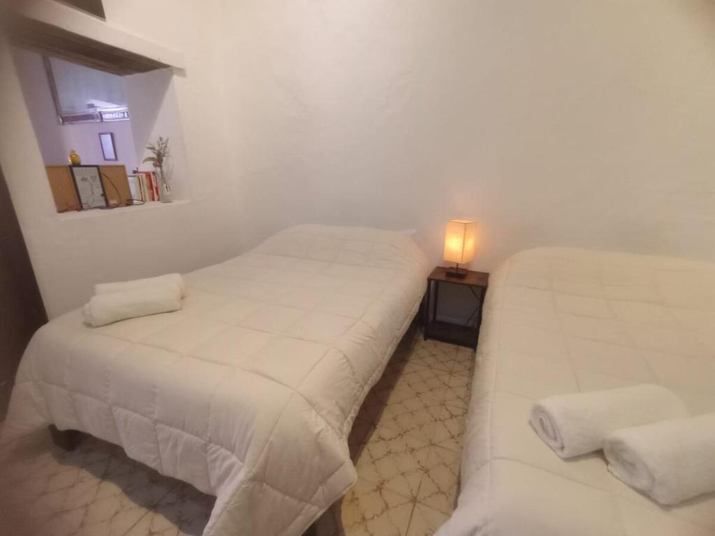 two beds in a room with a lamp on a table at Casa Posada Rústica - A 1 minuto del Jardín Unión in Guanajuato