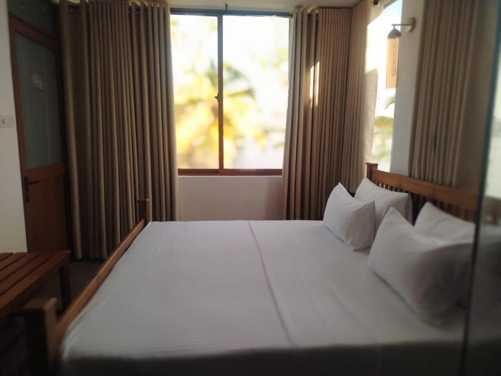 a bedroom with a large white bed with a window at The windsor Retreat in Moratuwa