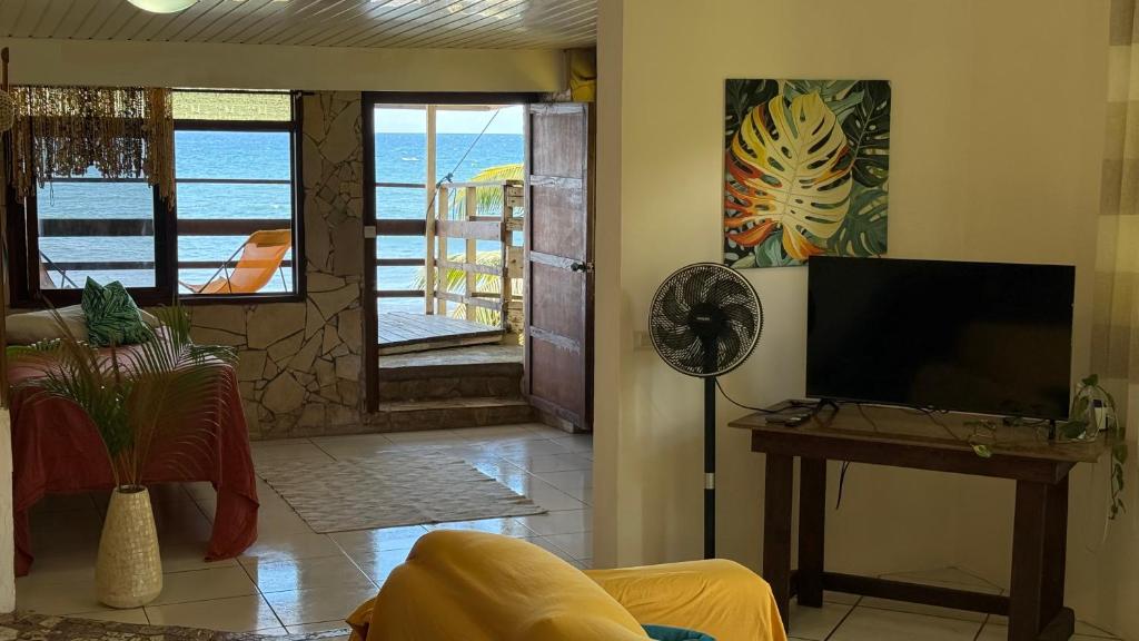 a living room with a flat screen tv and a table at Ave Surfing House in Mahina