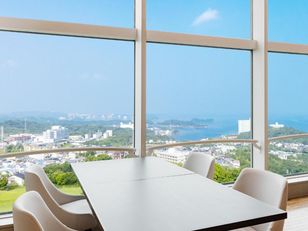 une table et des chaises blanches dans une chambre avec fenêtres dans l'établissement Nanki Shirahama Wan Wan Paradise Hotel, à Shirahama