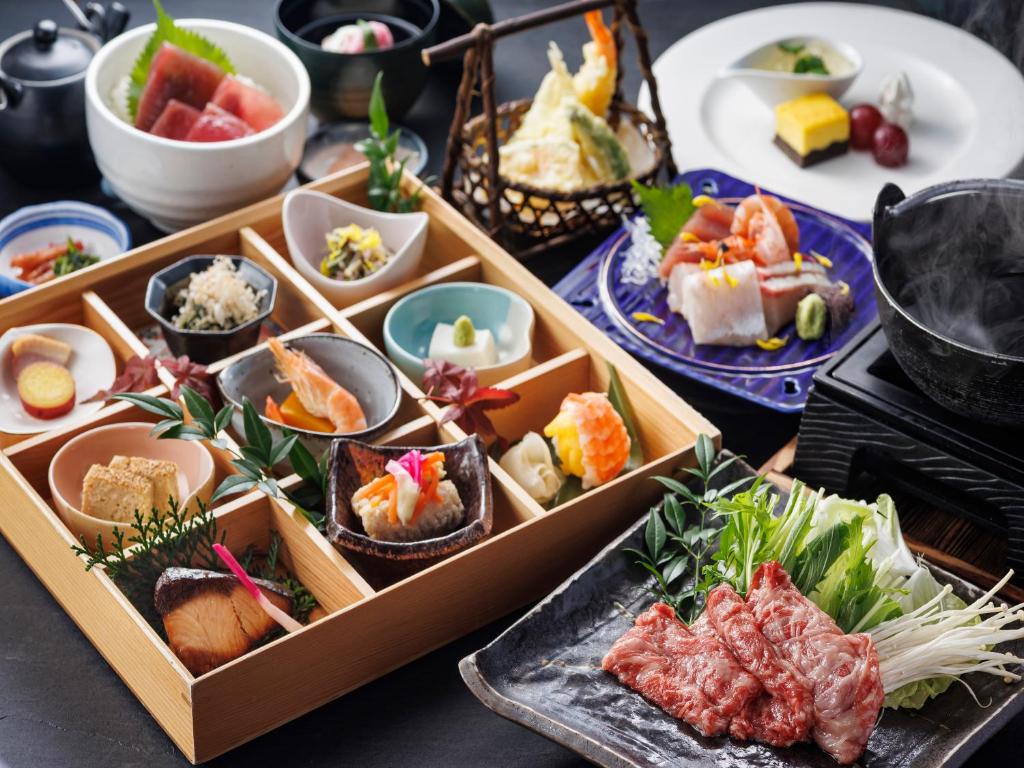 une table garnie d'assiettes de sushi et de bols de nourriture dans l'établissement Nanki Shirahama Wan Wan Paradise Hotel, à Shirahama