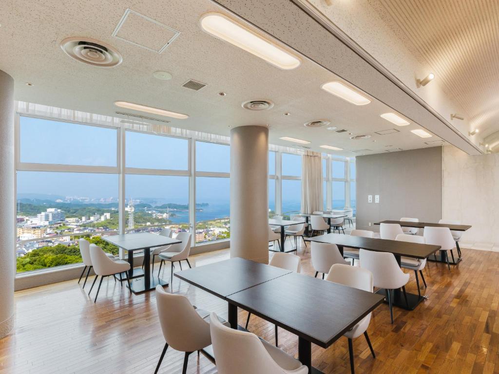 une cafétéria avec des tables et des chaises et de grandes fenêtres dans l'établissement Nanki Shirahama Wan Wan Paradise Hotel, à Shirahama