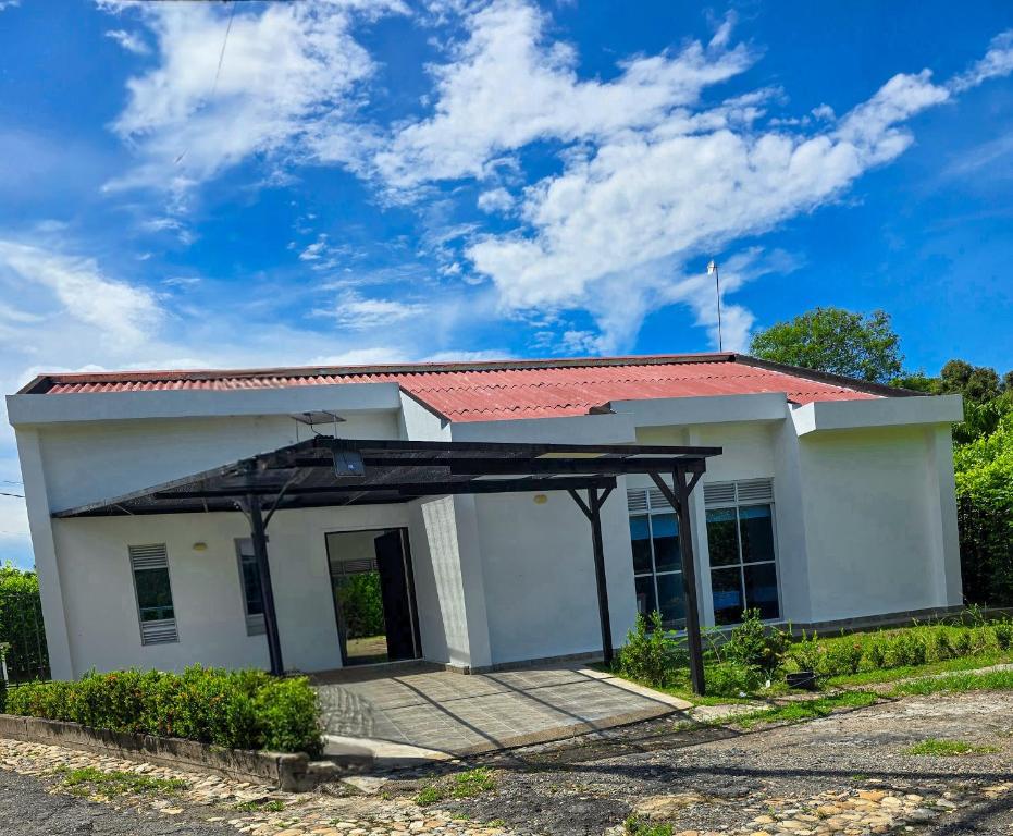 ein kleines weißes Haus mit einem roten Dach in der Unterkunft Casa de Descanso con Piscina y Jardín Ricaurte in Ricaurte