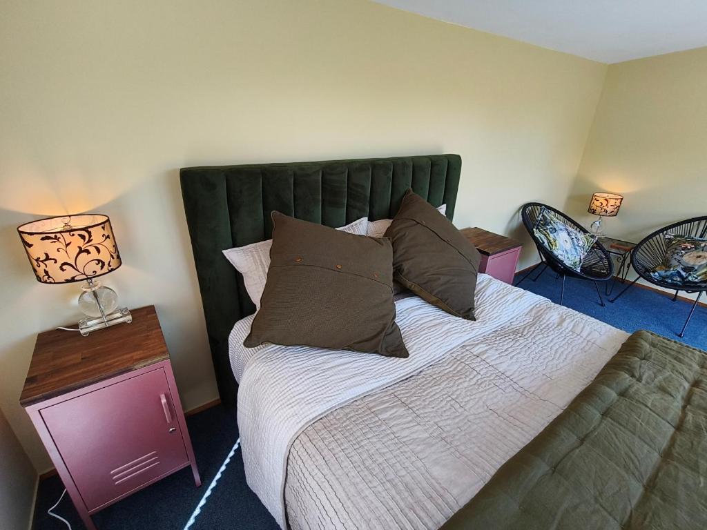 a bedroom with a bed with a green headboard and two lamps at Maungatapu Hut in Rai Falls
