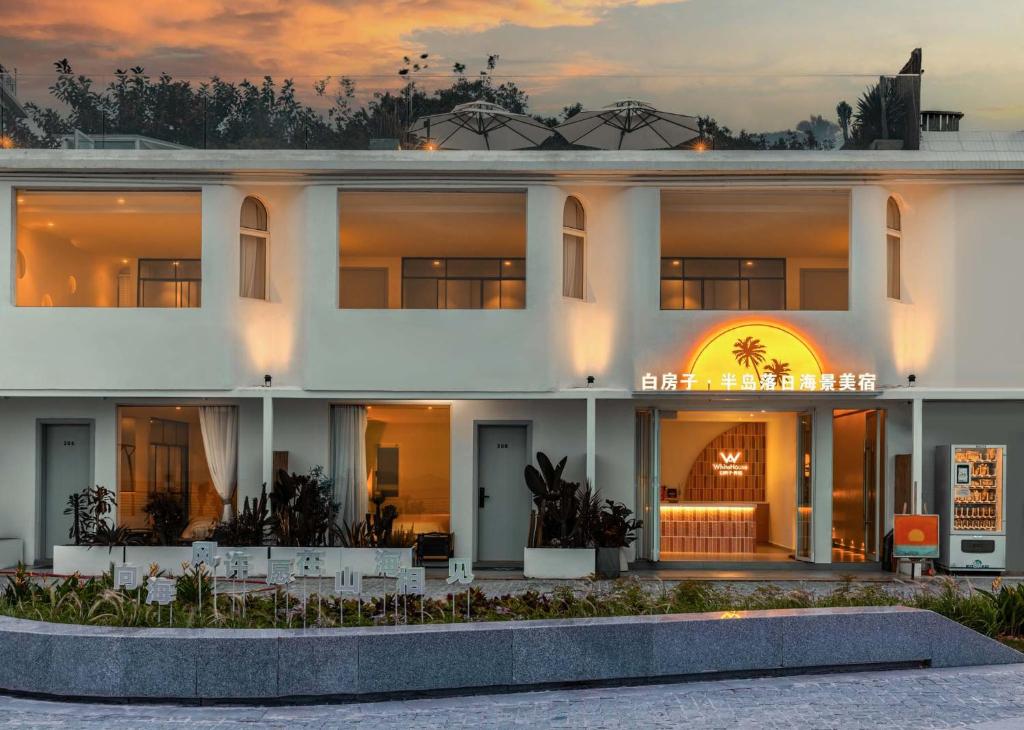 a large white building with a sunset in the background at Shenzhen White House Nan'ao Beach Seaview guesthouse in Youcaopeng