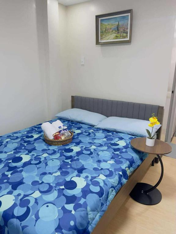 a bedroom with a bed with a blue blanket and a table at Potot Haven Dorm and Transient in Libmanan