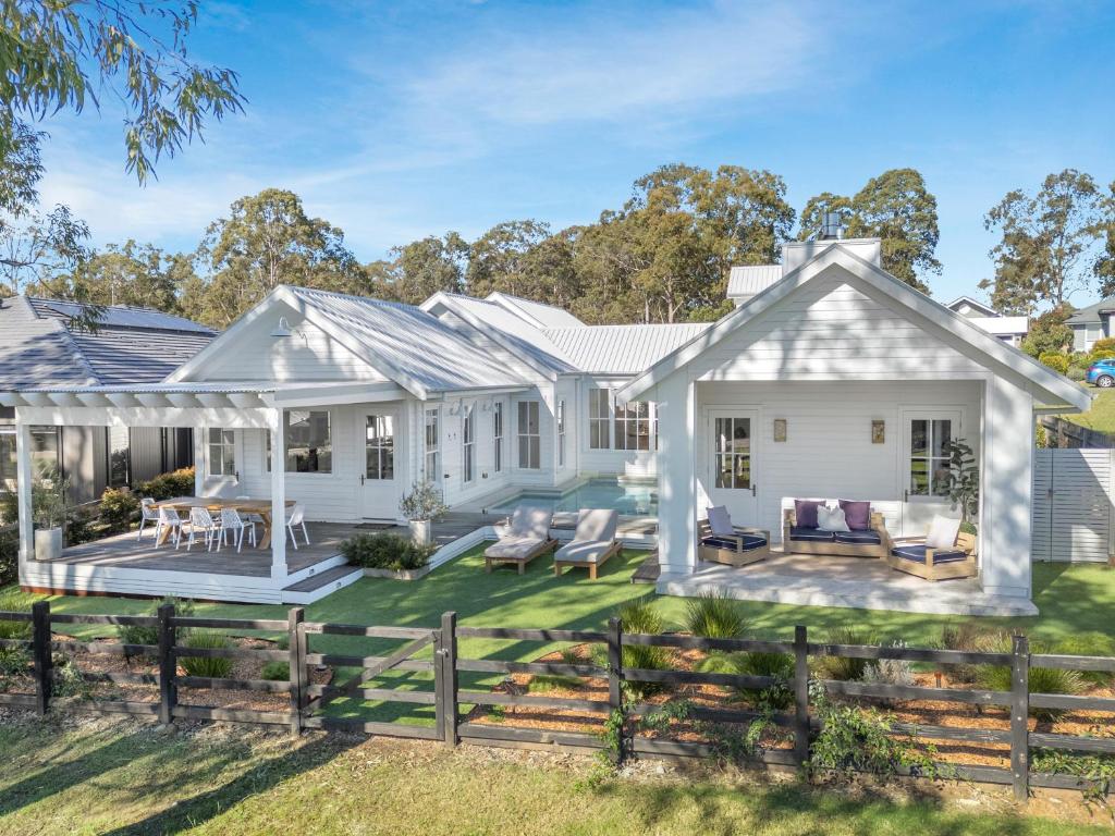 a white house with a patio and lawn at Farmhouse Hunter Valley in Pokolbin