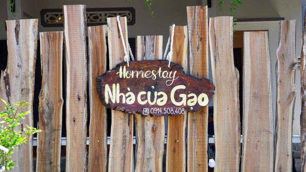 a sign is hanging on a wooden fence at Homestay Nhà Của Gạo in Ấp Thiẹn Ái