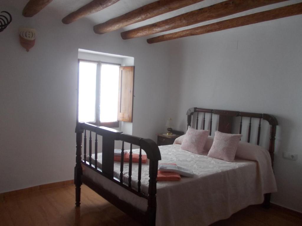 a bedroom with a bed with white sheets and a window at Casa de pueblo Godall in Godall