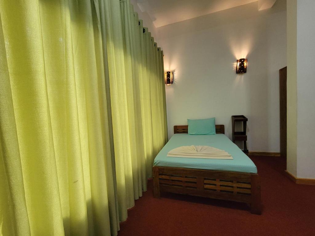Bett in einem Zimmer mit grünen Vorhängen in der Unterkunft River Resort by The Ceylon Adventure Sports Kithulgala in Kitulgala