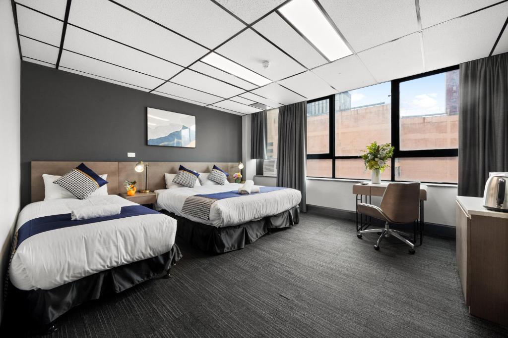 een hotelkamer met twee bedden en een bureau bij Cosmo on Bank in Adelaide