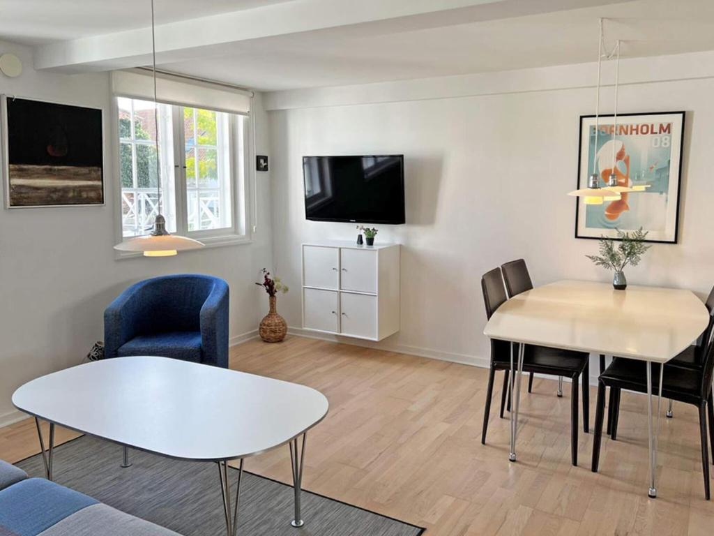 a living room with a table and chairs and a tv at 4 person holiday home in Svaneke in Svaneke