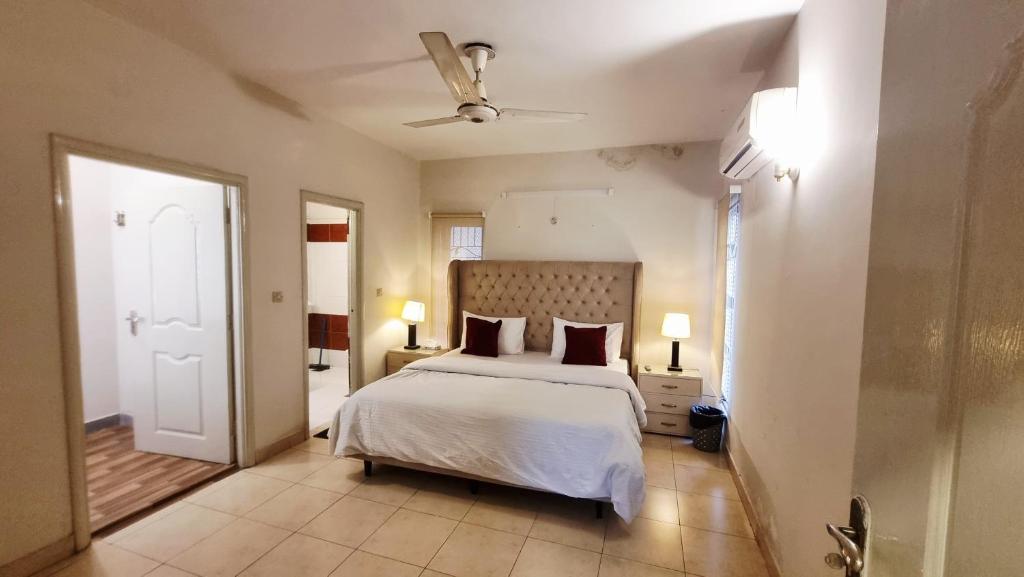 a bedroom with a bed with white sheets and red pillows at Haven Lodge - 4BR Luxurious Spanish Villa in Lahore in Lahore