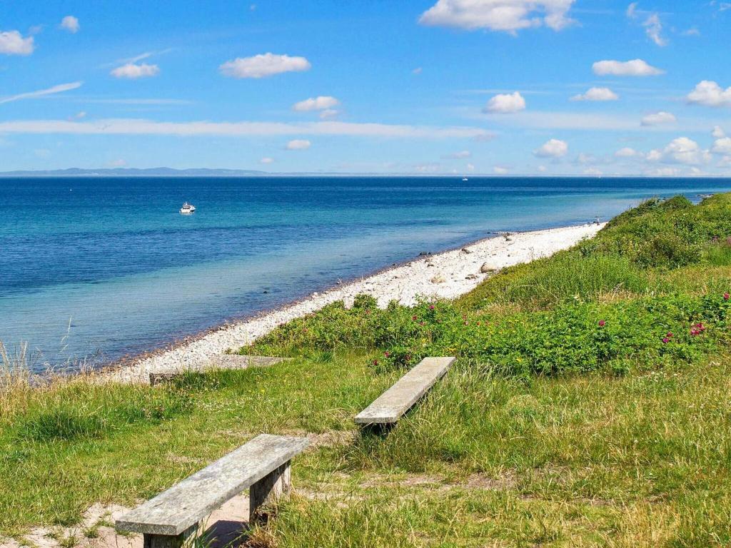 a bench sitting on the side of a beach at 6 person holiday home in Gilleleje in Gilleleje