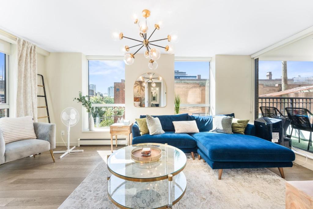 Una sala de estar con un sofá azul y una mesa de cristal. en Modern 2BR Apartment in Vibrant Chinatown, en Vancouver