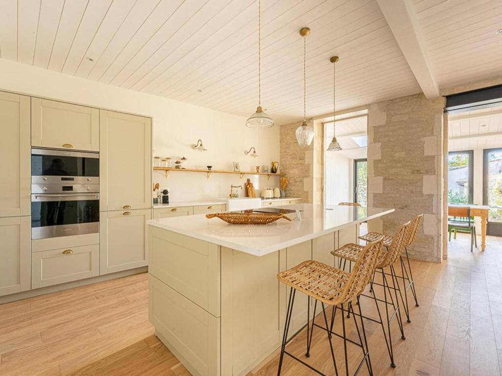 a kitchen with white cabinets and a island with bar stools at Maison de charme à La Flotte, 6 personnes, rénovée avec terrasse - FR-1-835-35 in La Flotte