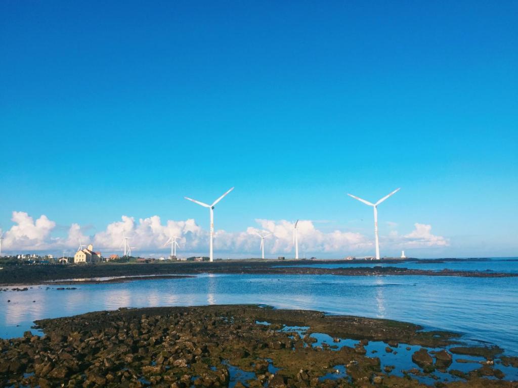 um grupo de moinhos de vento na praia com água em Bae Bae Guesthouse em Jeju