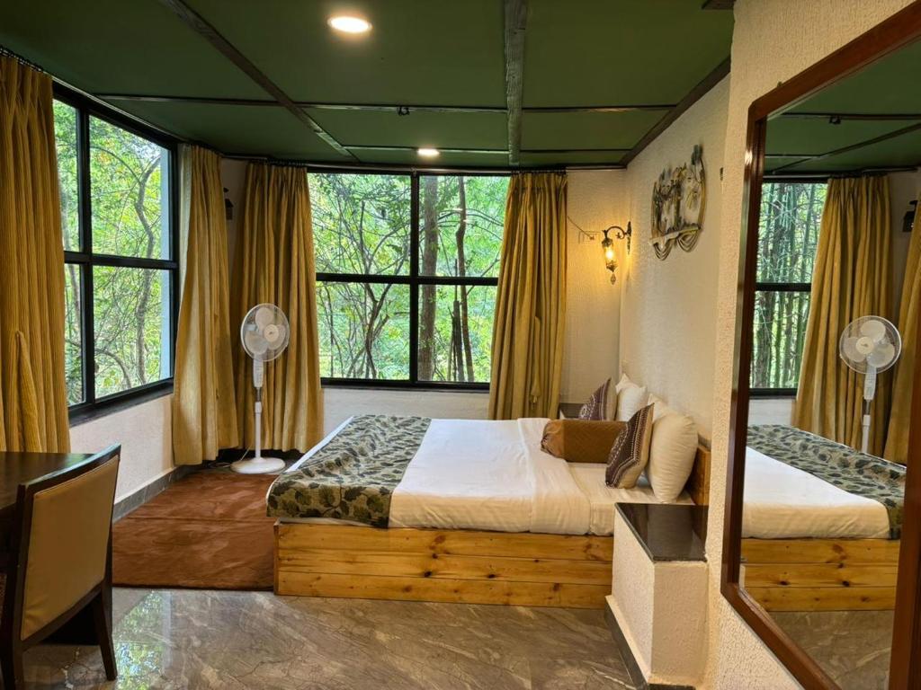 a bedroom with two beds in a room with windows at Pench Wilderness Camp Resort in Khawāsa