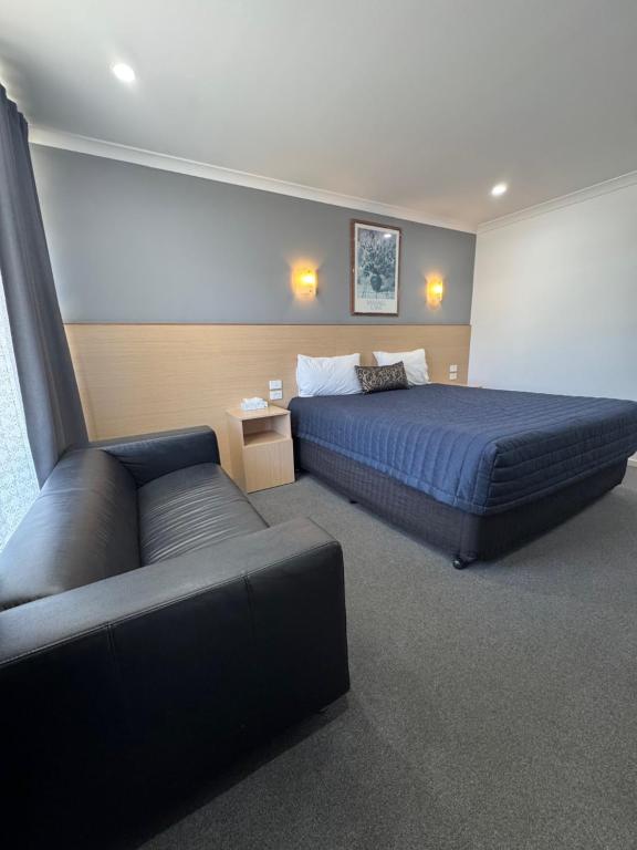 a bedroom with a bed and a couch at The Sands Motel in Adelaide