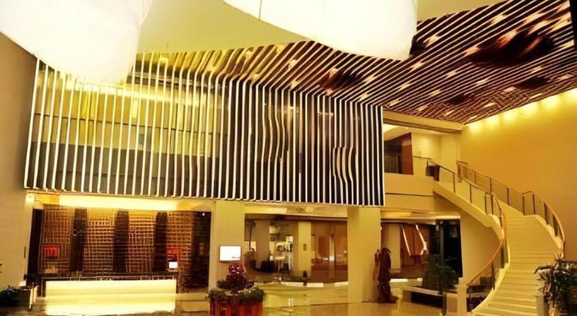 a lobby with a staircase in a building at Ramada Plaza by Wyndham Shaowu in Liaojiapai