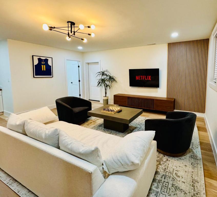 ein Wohnzimmer mit Sofa, Sesseln und Fernseher in der Unterkunft Modern Renovated Home in Charlottesville